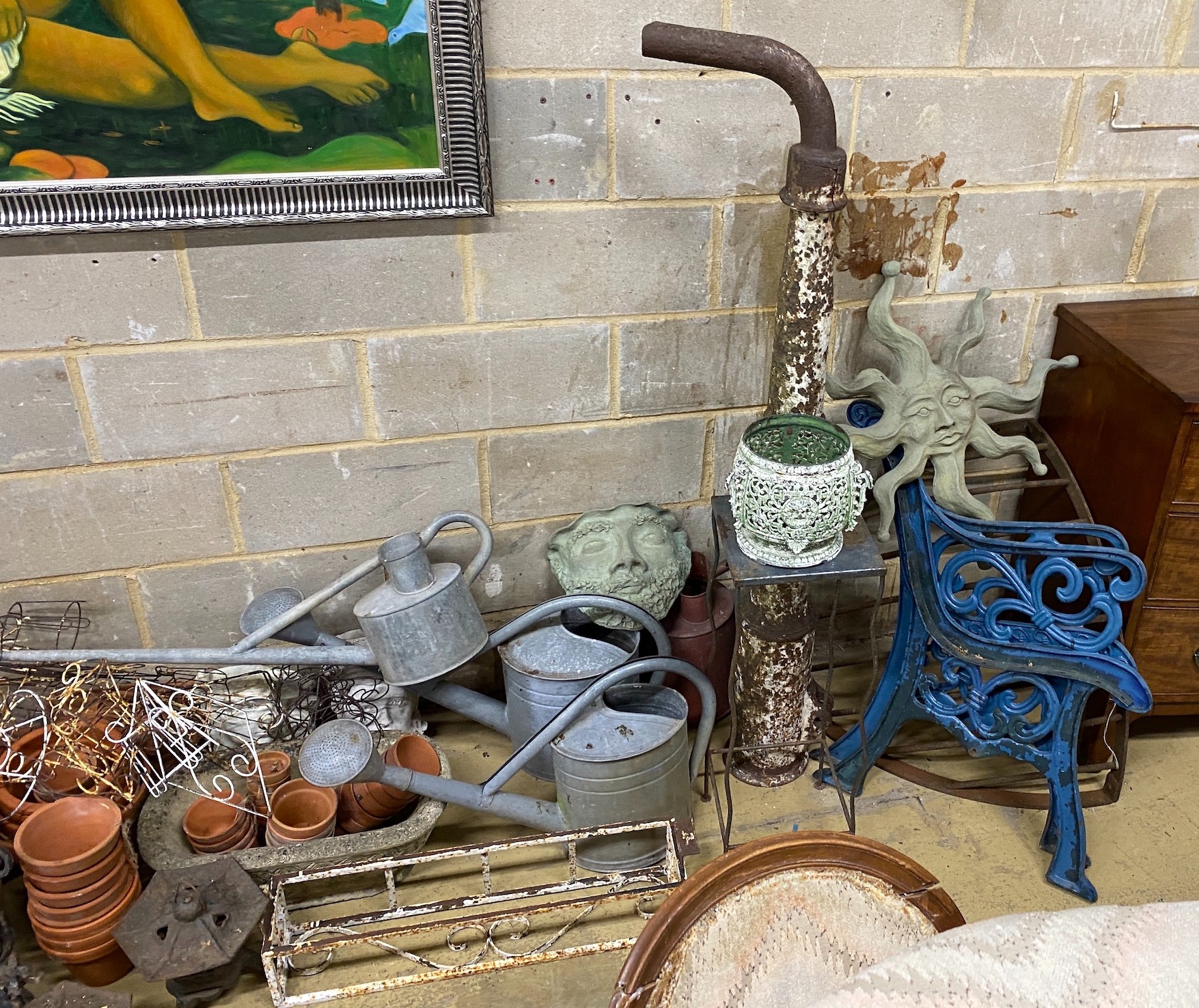 A large quantity of assorted garden ornaments, terracotta pots, galvanised watering cans, bench ends, etc.
